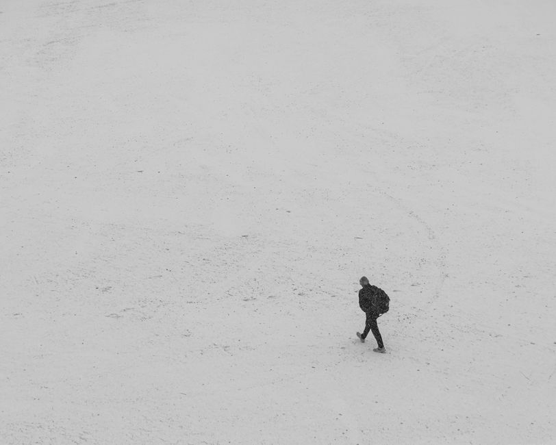 A person warmly dressed in winter gear, including a thermal jacket, hat, and gloves, exploring snowy Vilnius.