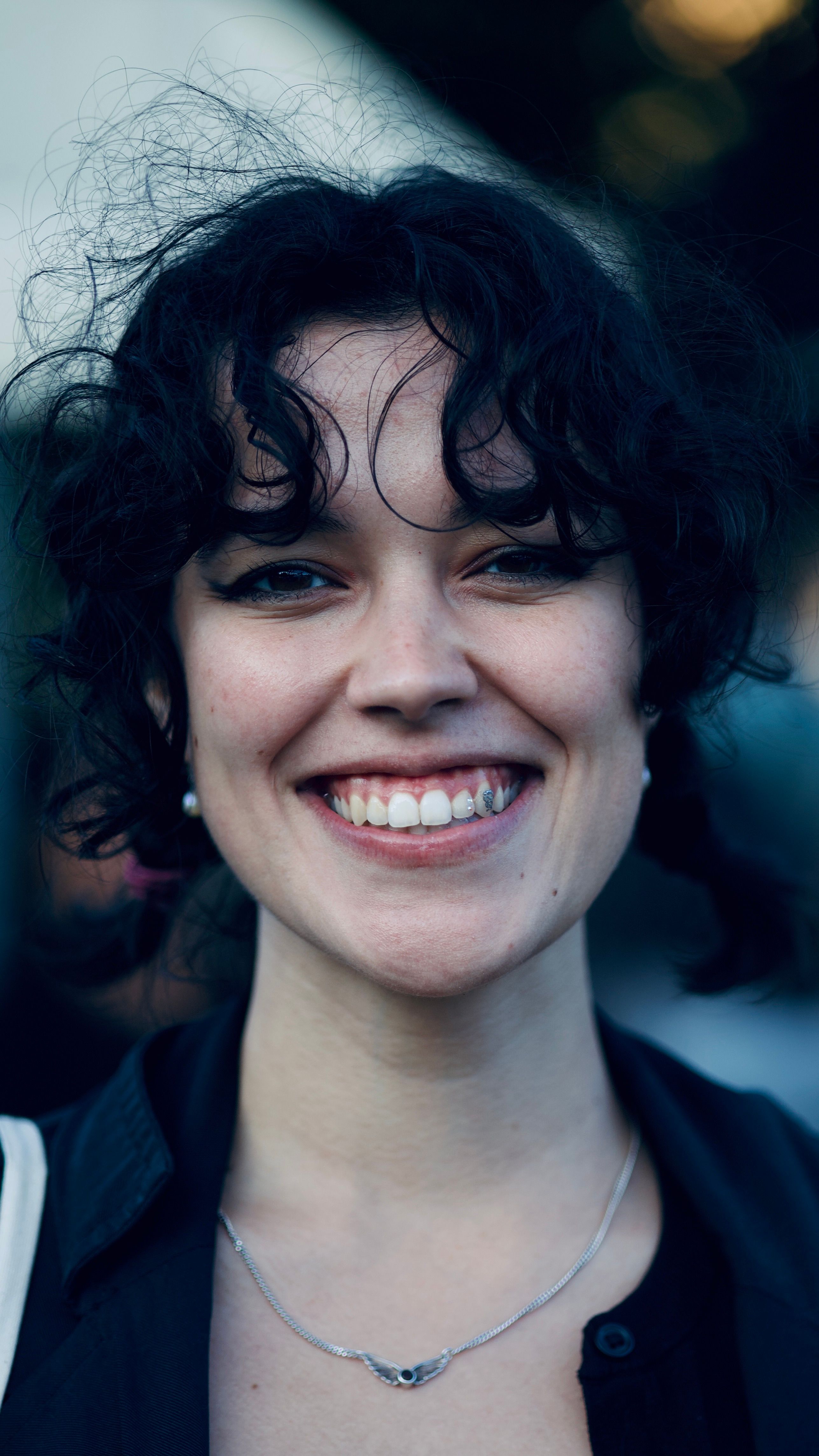 Close-up portrait capturing the joy and natural beauty of a young woman with curly hair outdoors.
