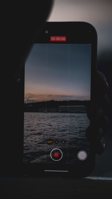Captured twilight scene with smartphone silhouette recording twilight over water, creating a reflective and dramatic effect.