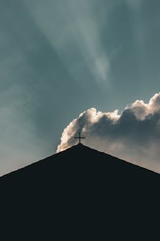 A church silhouette with a cross against a dramatic cloudy sky, capturing a spiritual and serene atmosphere.