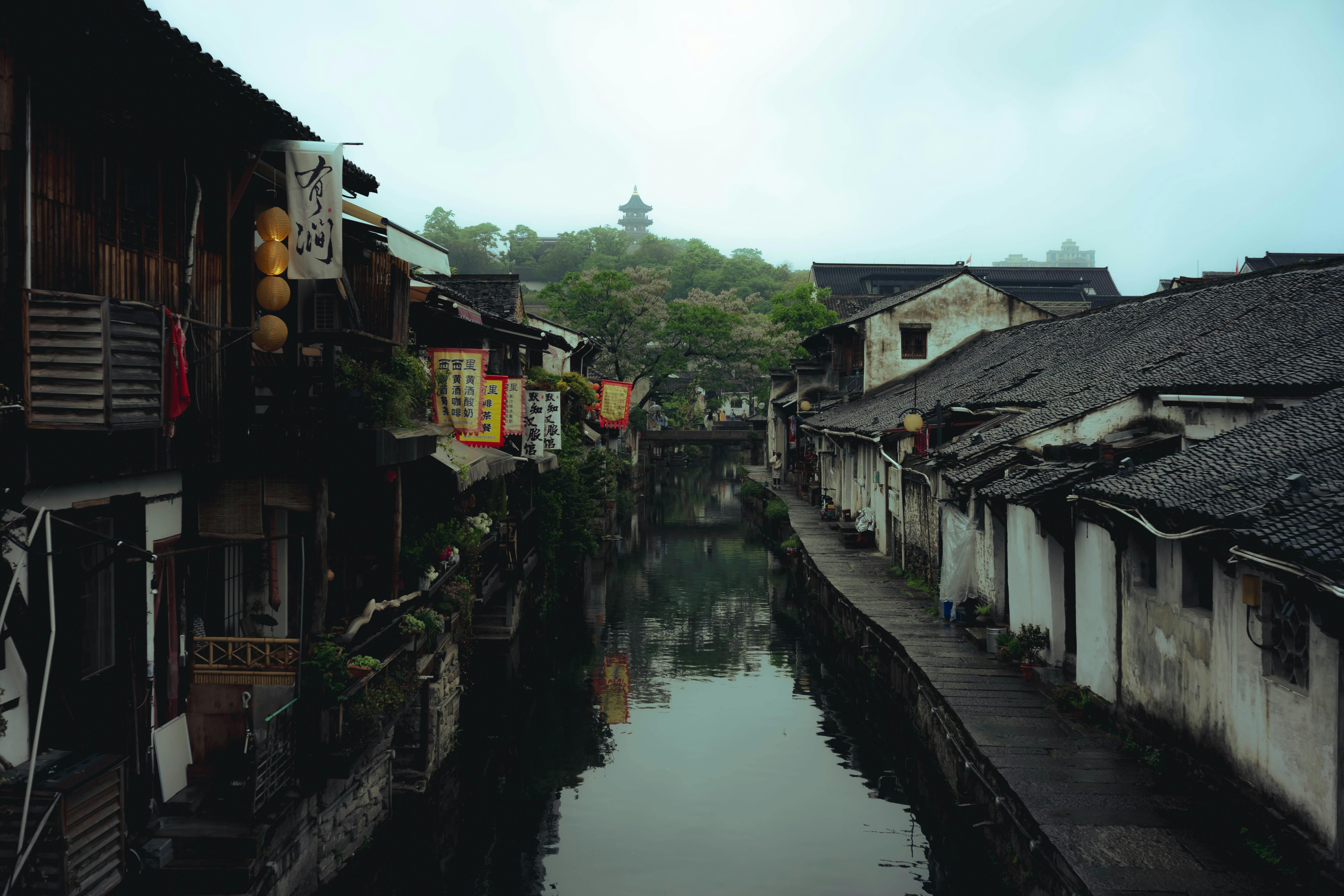 Scenic view of a traditional Chinese canal flanked by historic buildings and lush greenery.