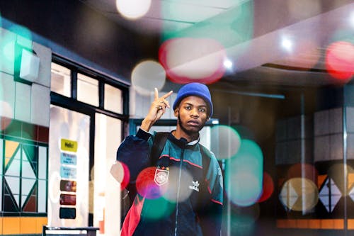 Free Photo of Man in Beanie Hat and Multicolored Jacket Posing While Doing the Peace Sign Stock Photo