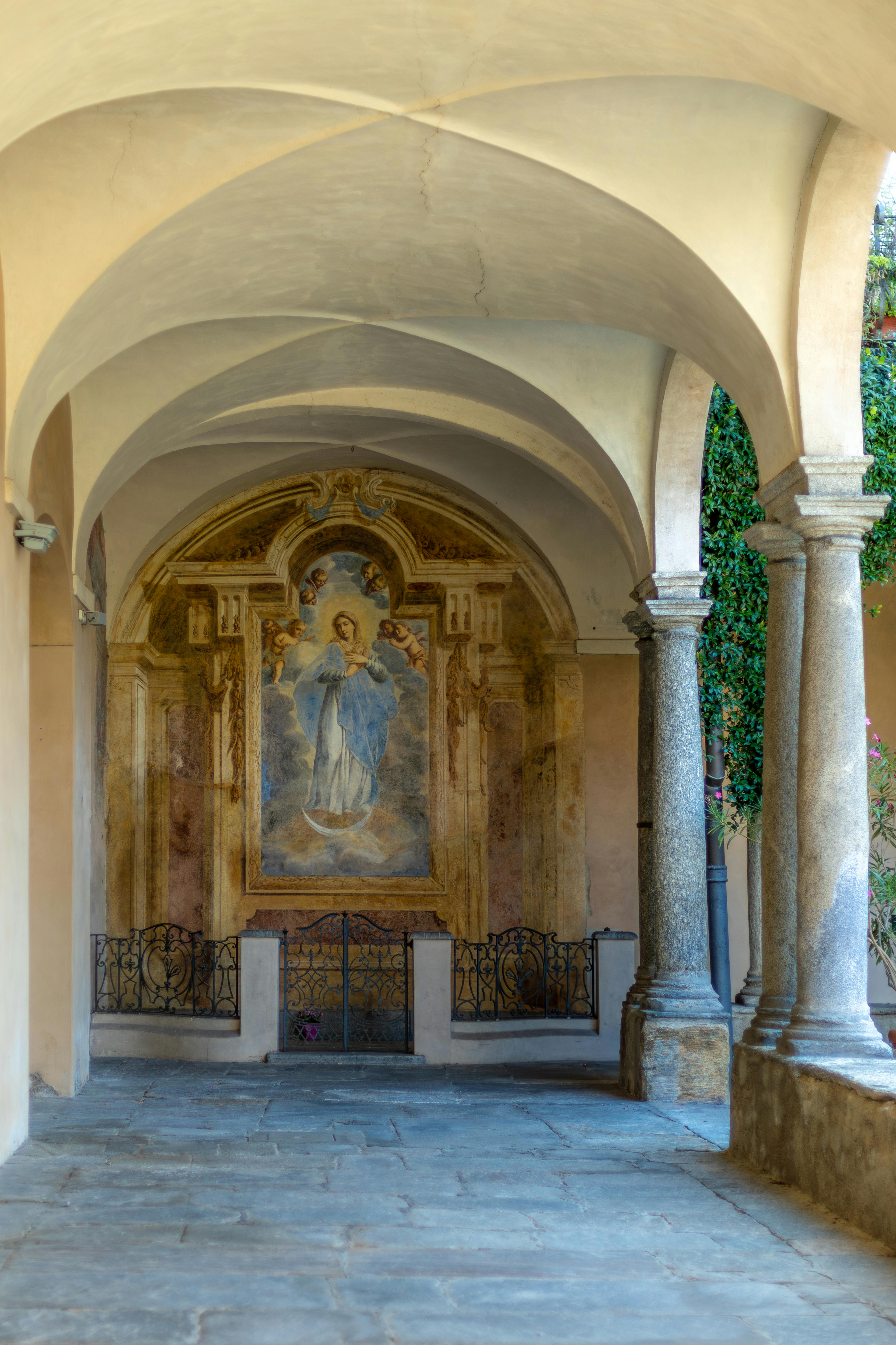 a hallway with arches and a painting on the wall