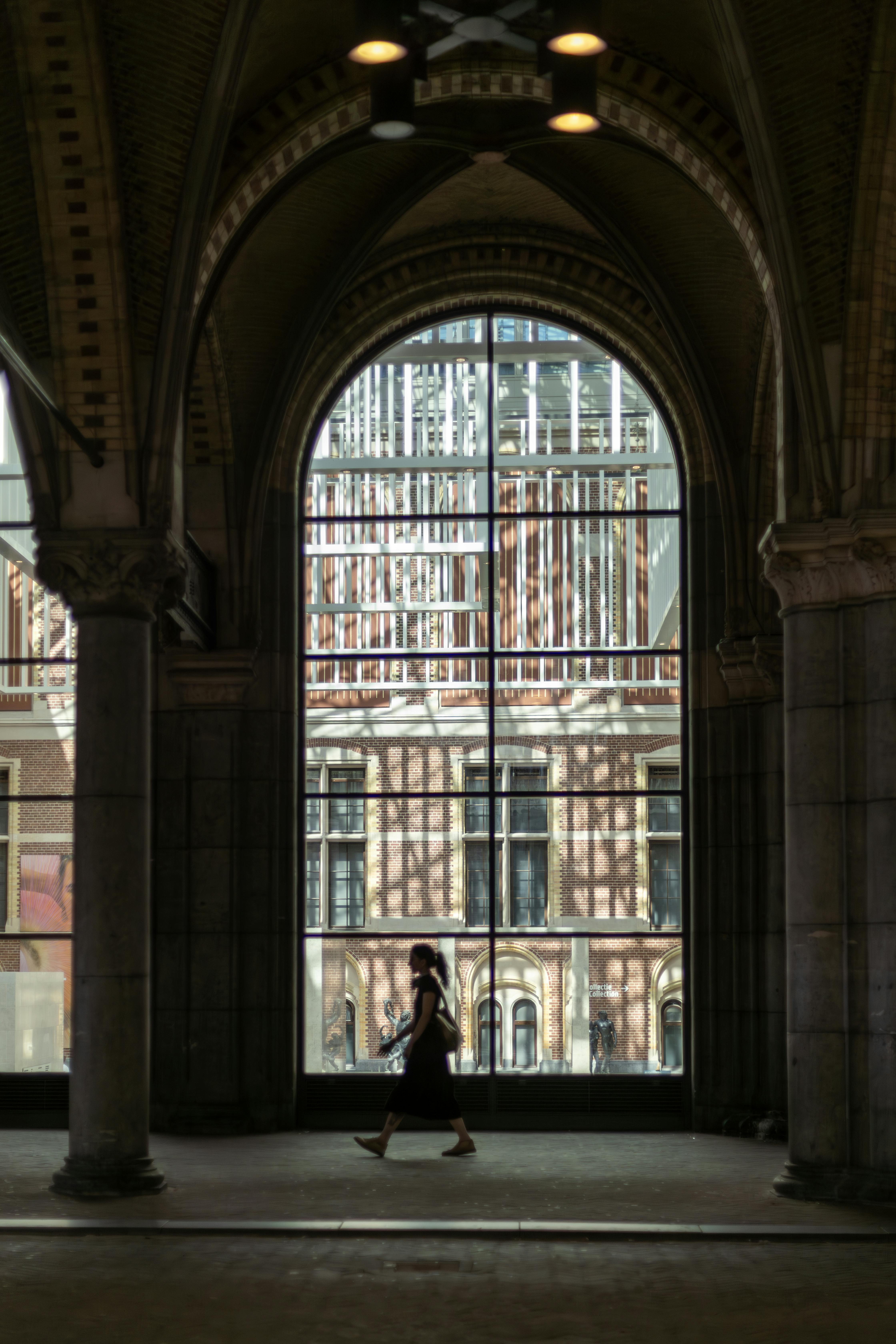 A silhouette of a woman walking through a stunning archway in an urban setting, capturing architectural beauty.