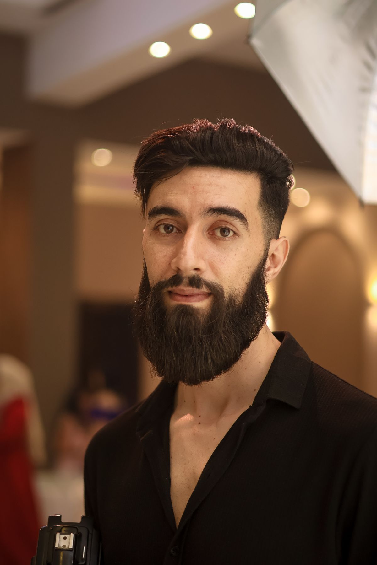 Retrato de homem jovem com barba bem desenhada e cabelo estilizado em ambiente interno