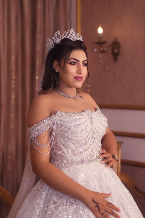 Free Stunning bride in a luxurious white gown with intricate beadwork, posing indoors. Stock Photo