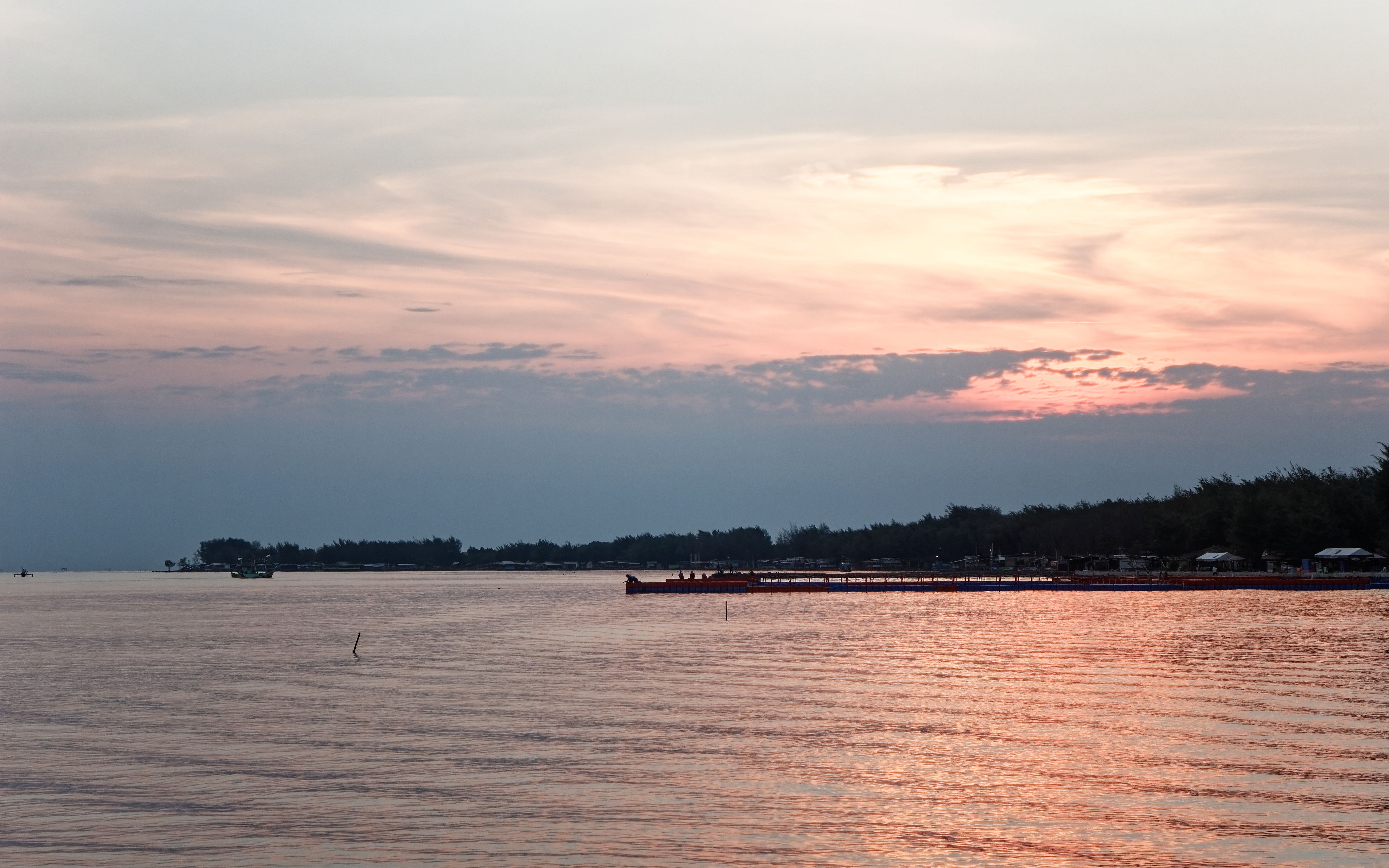 Beautiful sunset over the tranquil waters of Tegal Beach, Central Java, creating a peaceful landscape.