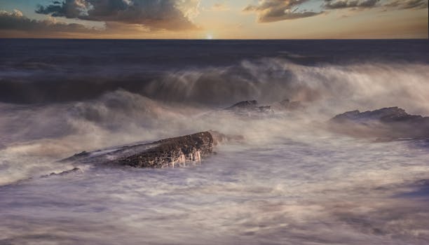 Captivating seascape with waves crashing on rocks under a dramatic sunset sky.