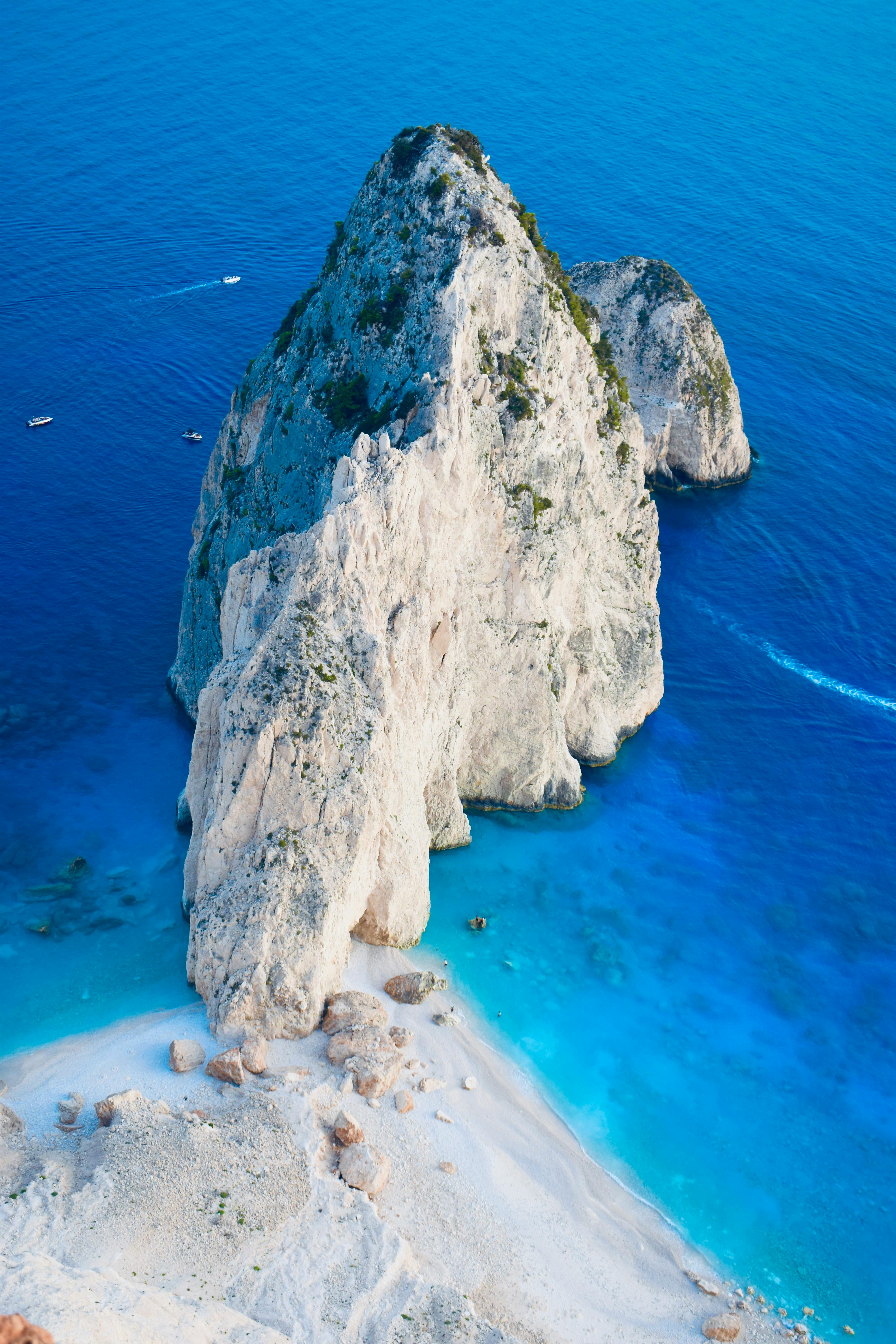 Breathtaking aerial view of a limestone rock formation surrounded by clear blue sea and sandy beach.