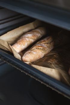 Close-up of freshly baked baguettes in an oven showcasing artisanal bakery techniques.