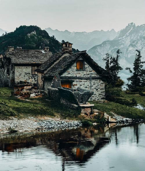 Free A quaint stone cottage in Switzerland by the lake, set against majestic mountains. Stock Photo