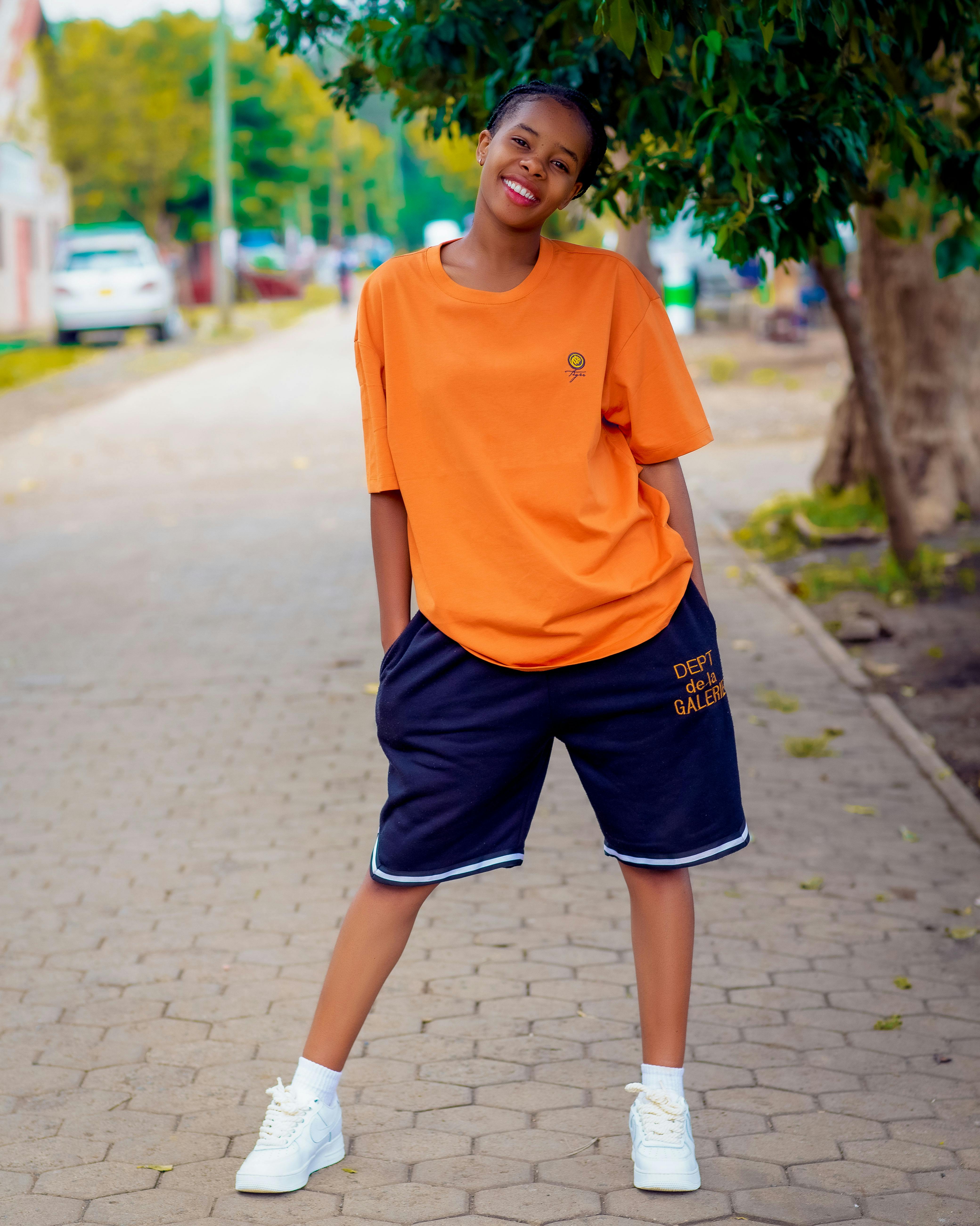 a young woman in an orange shirt and black shorts