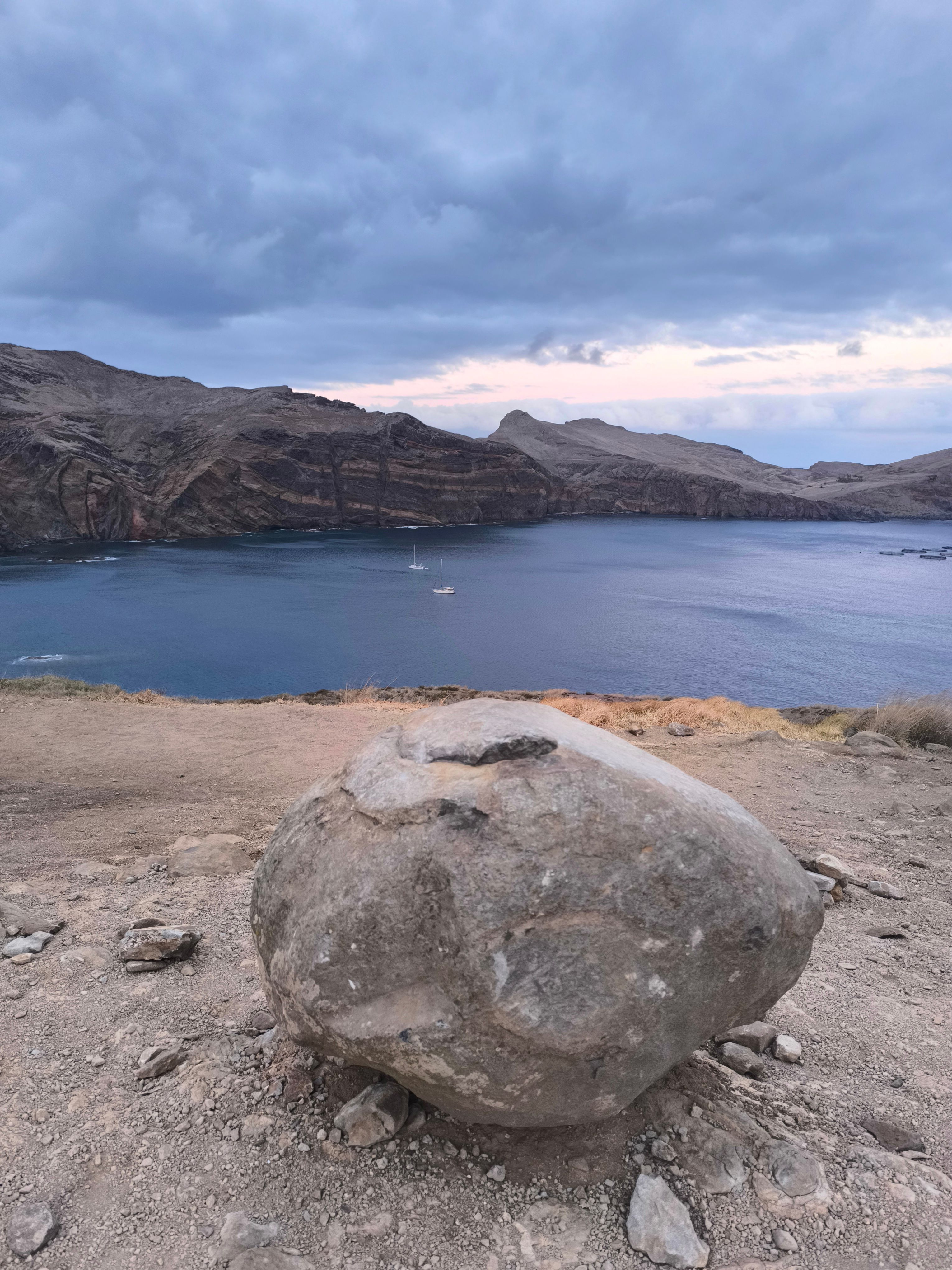 Scenic coastal landscape of Madeira, Portugal featuring rocky terrain and tranquil waters under a cloudy sky.
