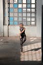 一名女子在废弃的建筑中优雅地跳舞，阳光透过窗栅