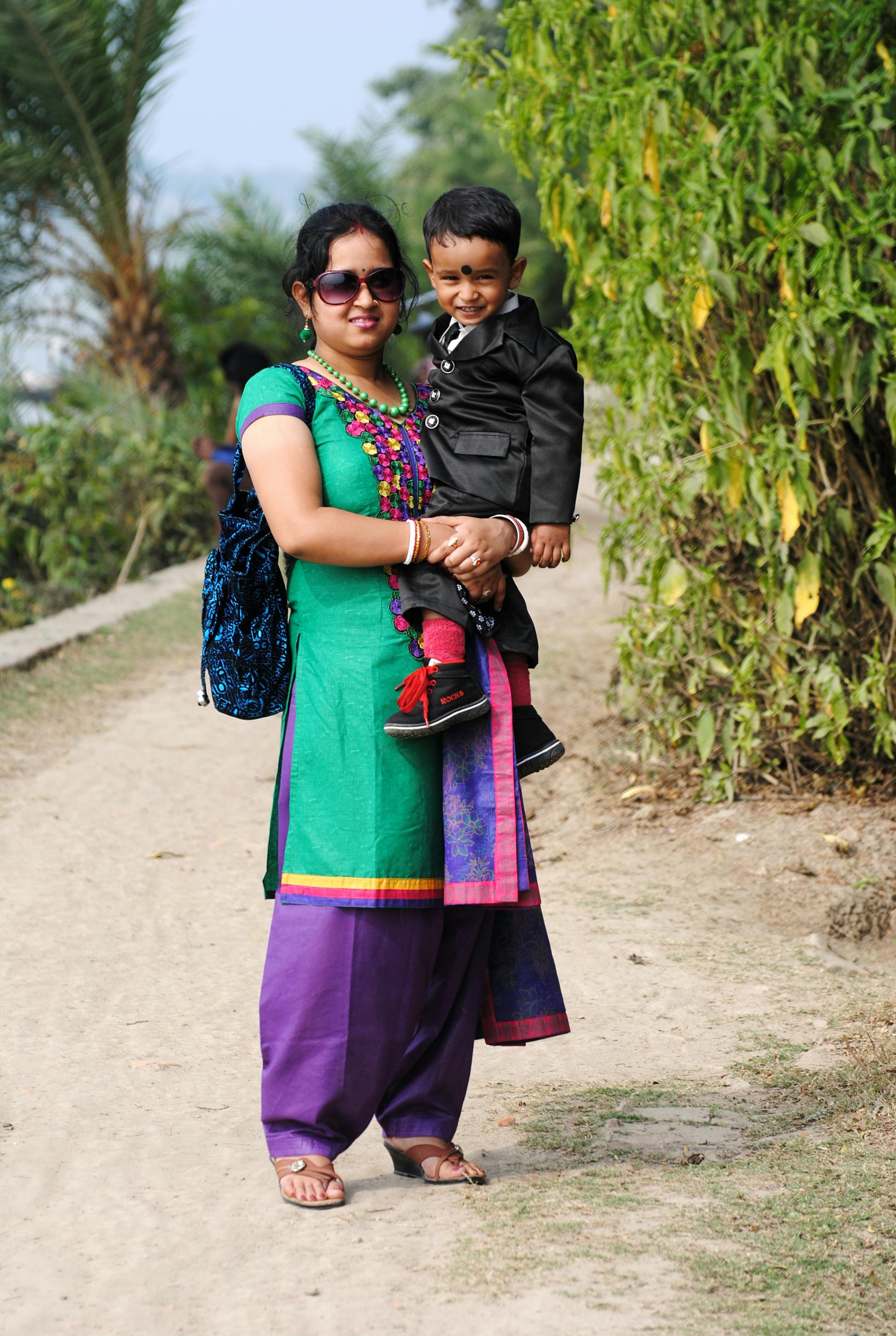 a woman in a green and purple sari holding a child