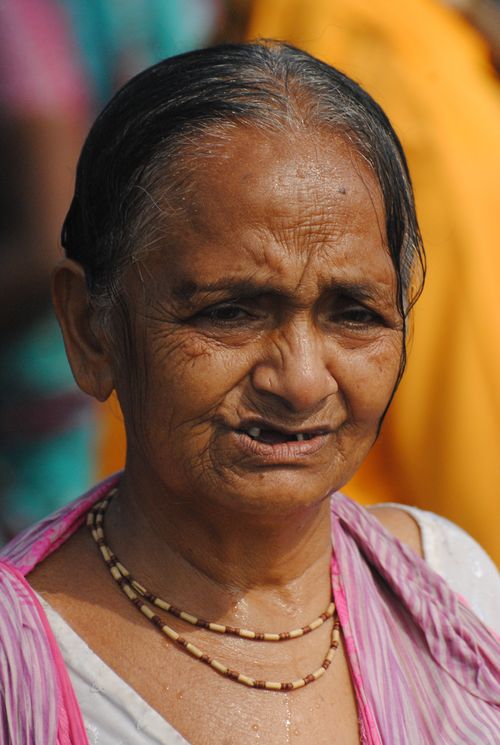 Free Close-up portrait of an elderly woman with a gentle expression wearing traditional jewelry outdoors. Stock Photo