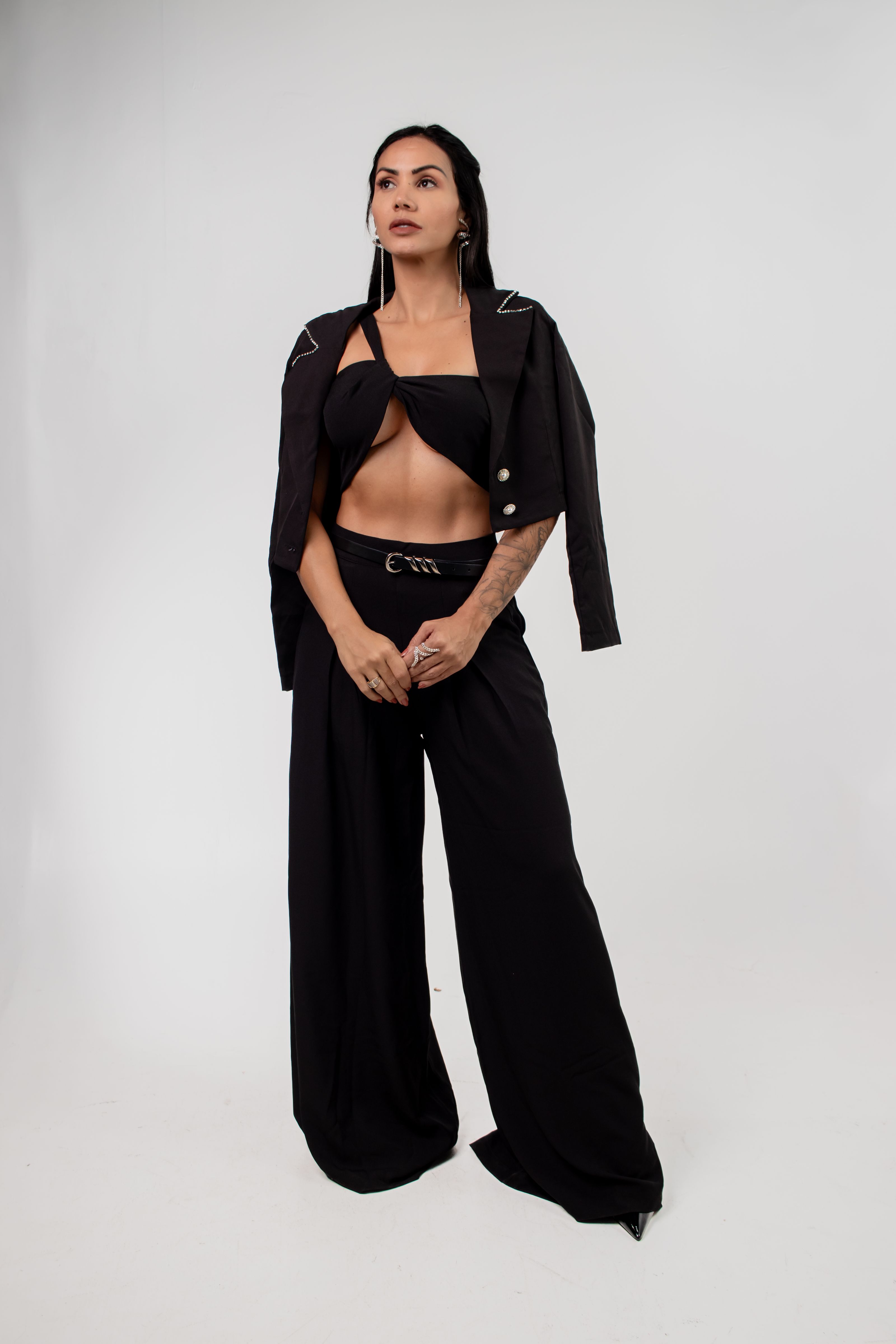 Jovem elegante em um traje preto da moda posando com confiança.