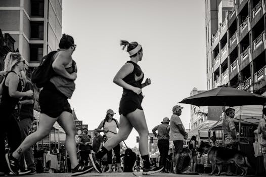 Black and white photo of people jogging and walking in a lively city street.