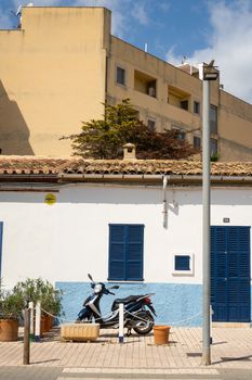 Charming urban street scene with a scooter parked near colorful buildings with blue shutters.