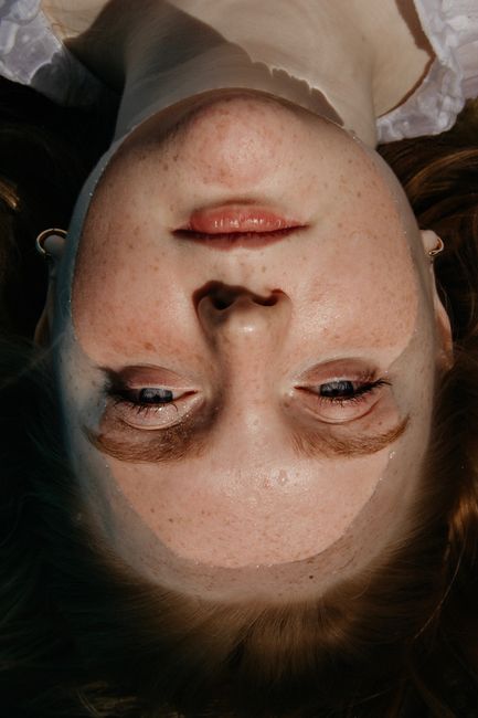 Artistic close-up portrait of a woman's face with freckles, showcasing natural beauty.