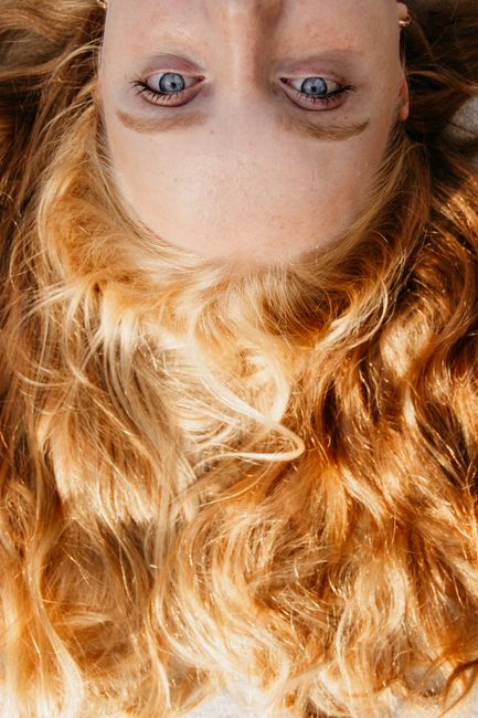 Up-close view of golden blonde hair and blue eyes with soft lighting.