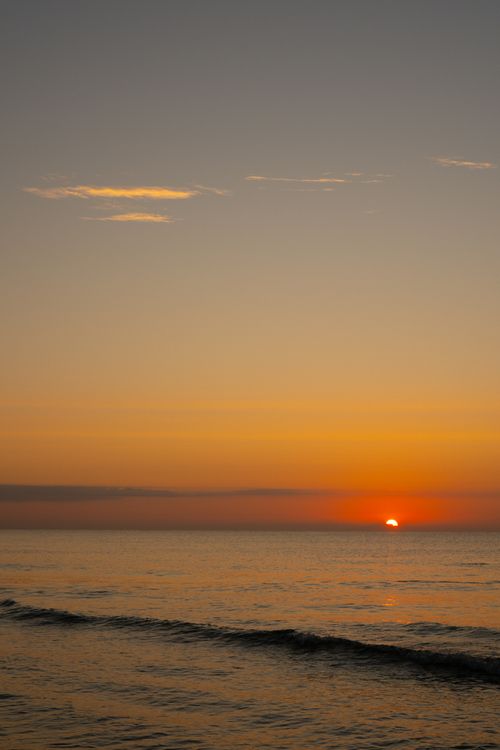 Free A breathtaking sunset over a tranquil ocean, casting vibrant hues across the sky and water. Stock Photo