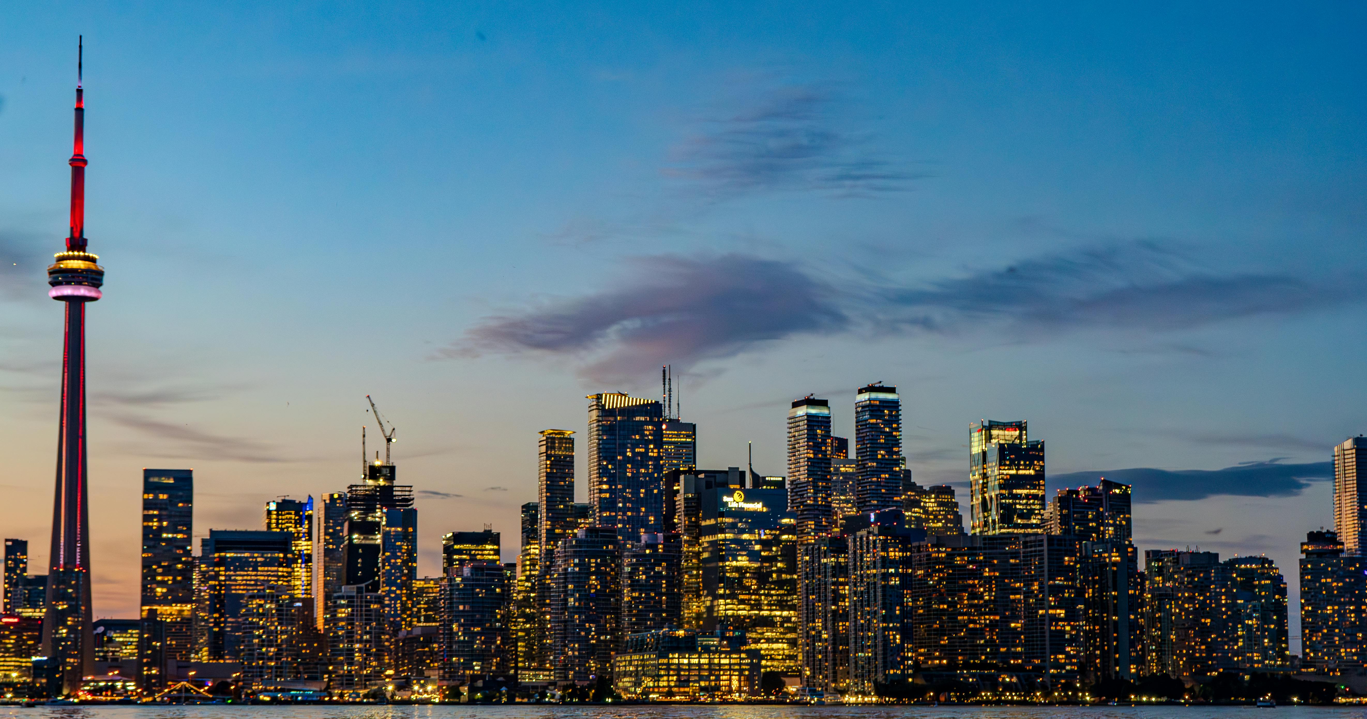 the toronto skyline at dusk with the water in the foreground