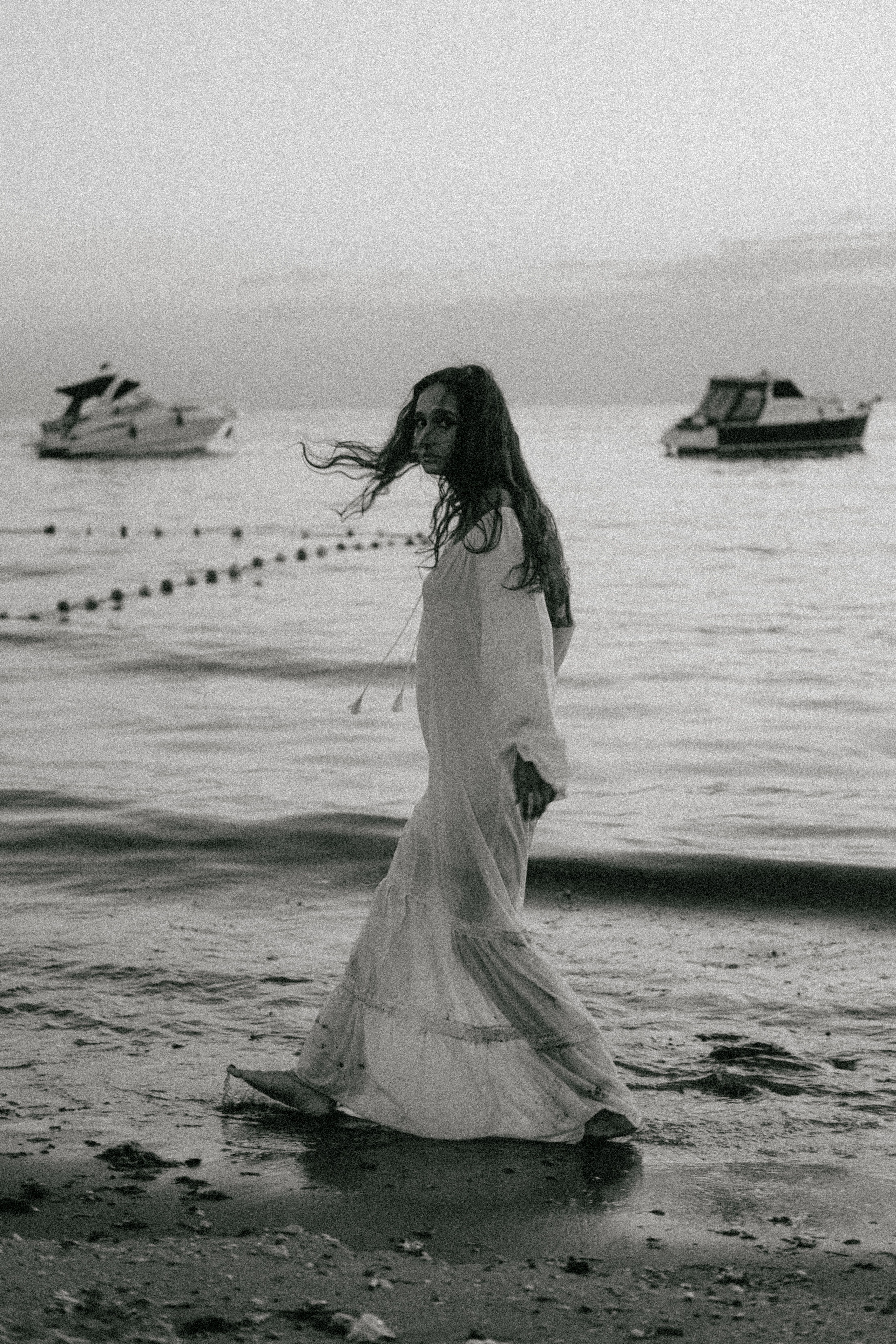 A woman in a long dress walking on the beach  Free Stock Photo