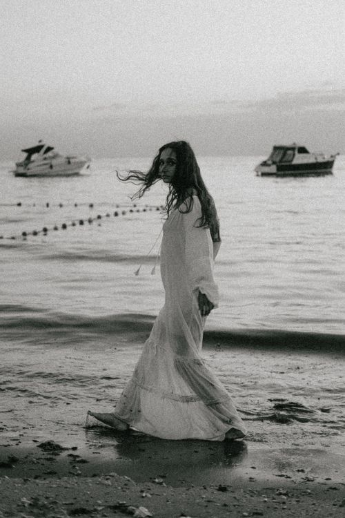 A woman in a long dress walking on the beach Free Stock Photo A woman in a long dress walking on the beach Free Stock Photo