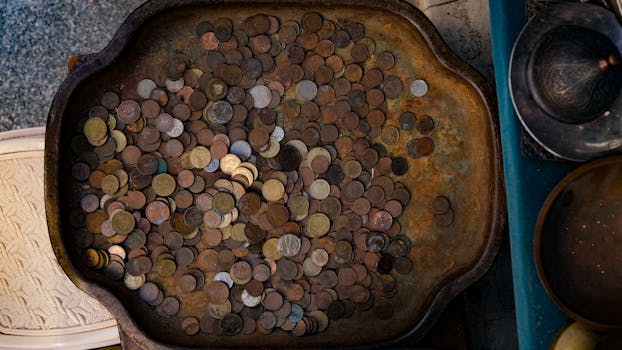 A rustic tray filled with various vintage coins, showcasing rich metallic textures and patterns.