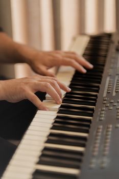 Musician's hands gracefully playing a digital piano keyboard indoors.
