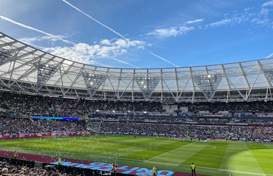 A packed London Stadium hosts a thrilling soccer match, with vibrant atmosphere and engaged crowd.