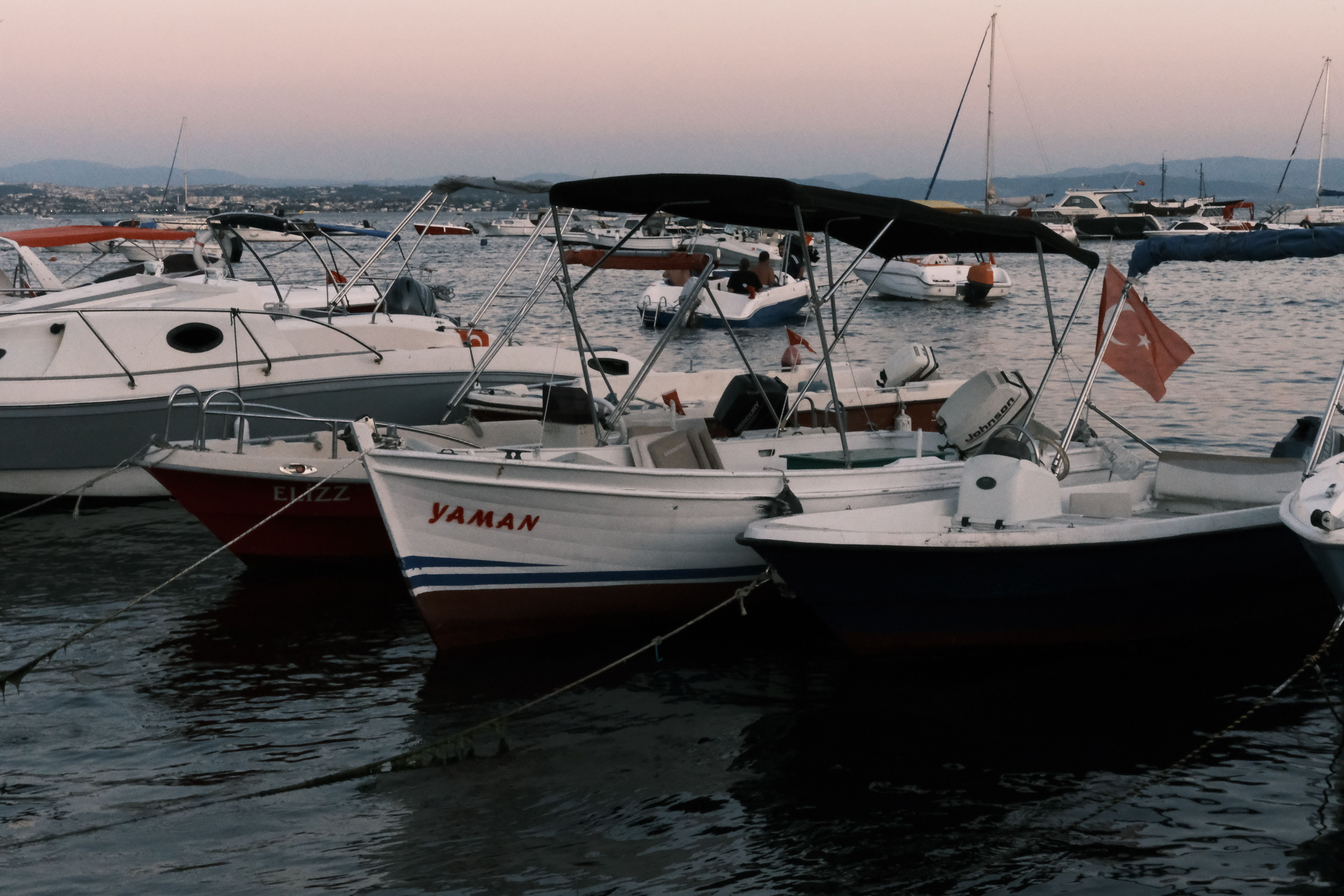 A peaceful harbor scene with moored boats at sunset, showcasing nautical beauty and calm waters.