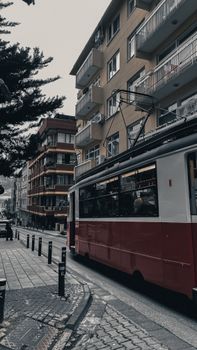 A classic red tram travels through a busy urban street, capturing the essence of city life.