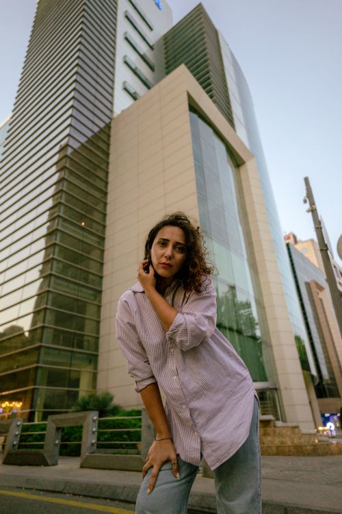 Free A young woman poses in front of a modern skyscraper in Baku, Azerbaijan, at dusk. Stock Photo