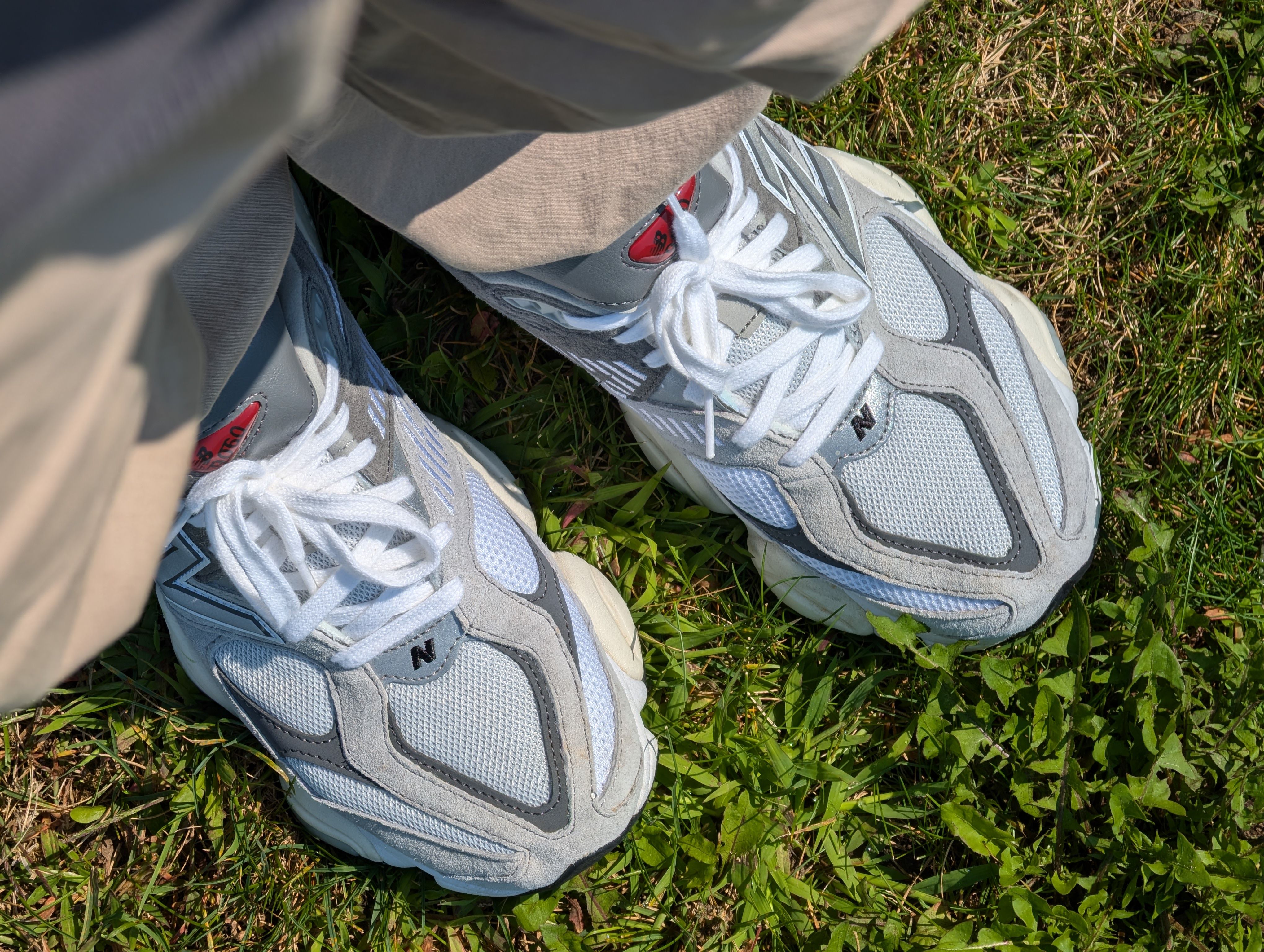 A pair of white sneakers on grass, perfect for a summer outdoor activity.