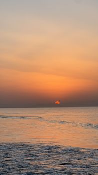 Peaceful ocean sunset with vibrant sky hues reflecting over calm waves.