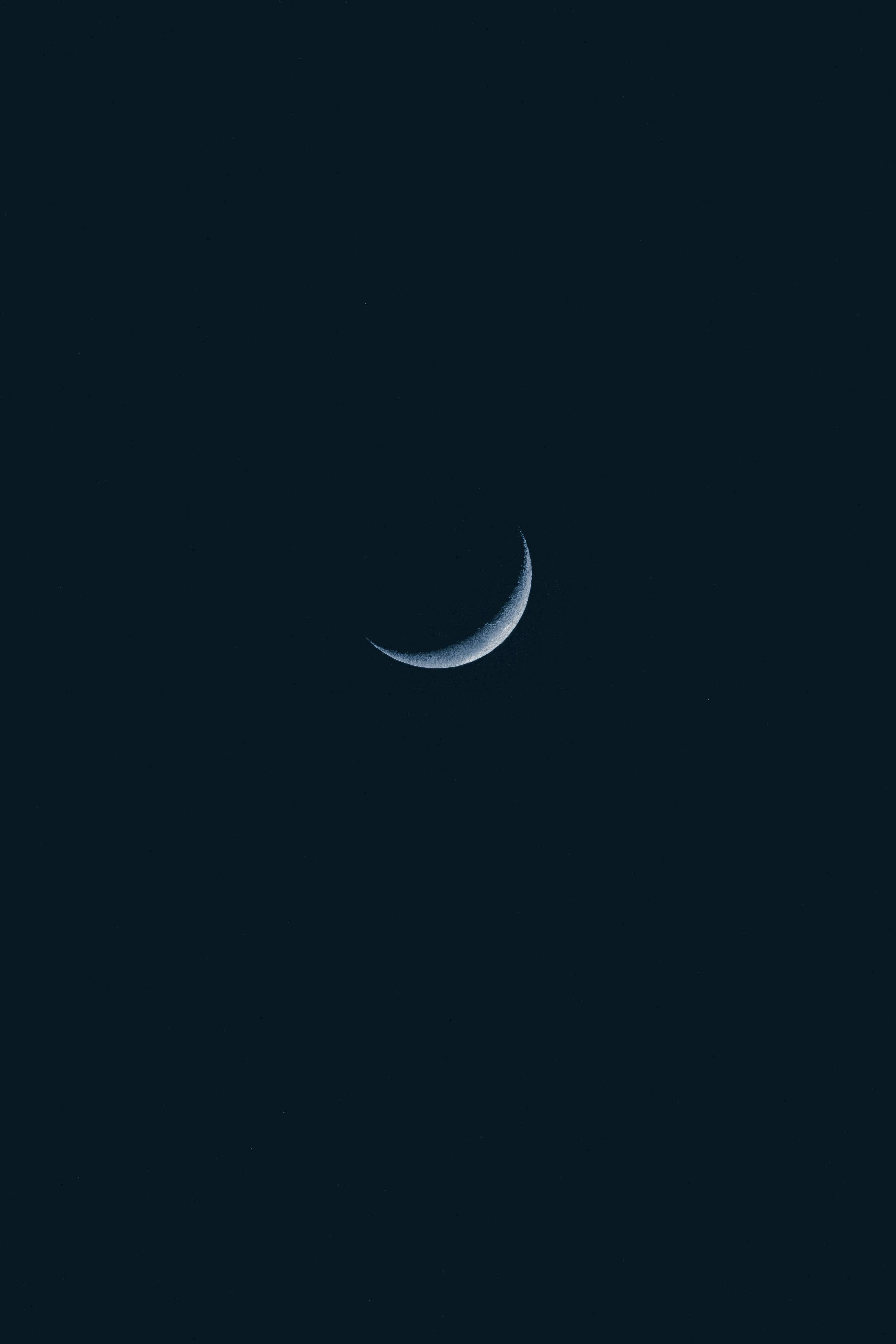 Minimalist photo of a crescent moon in the dark night sky, captured in Aracati, Brazil.