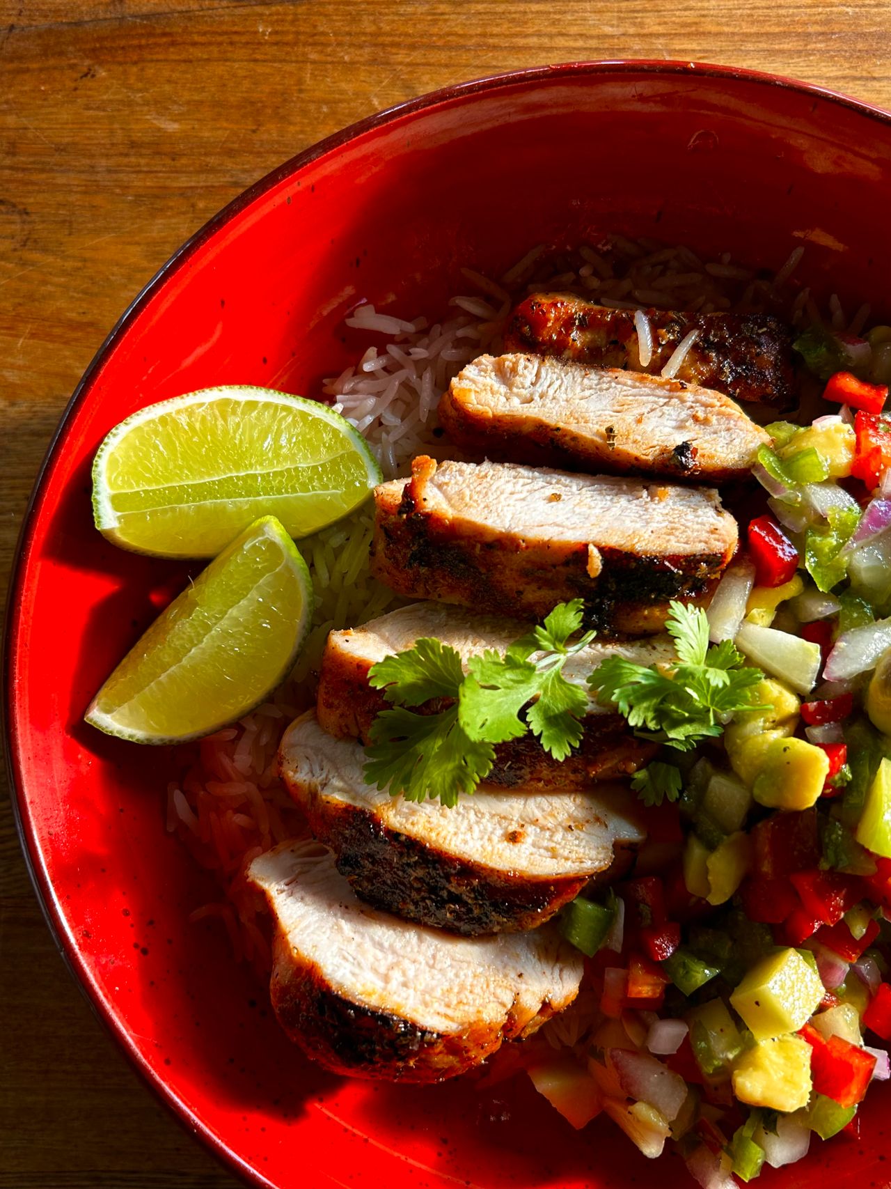 Grilled Cuban chicken with fresh salsa and lime slices on a red plate