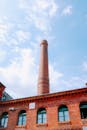 一座工业建筑引人注目，高大的砖砌烟囱直插充满活力的蓝天