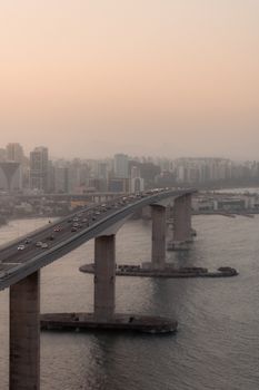 Aerial view of the Rio-Niterói Bridge in Rio de Janeiro at sunset with cityscape background.