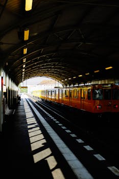 一辆色彩鲜艳的黄色列车正停靠在宁静的城市车站，展现了现代交通的风貌