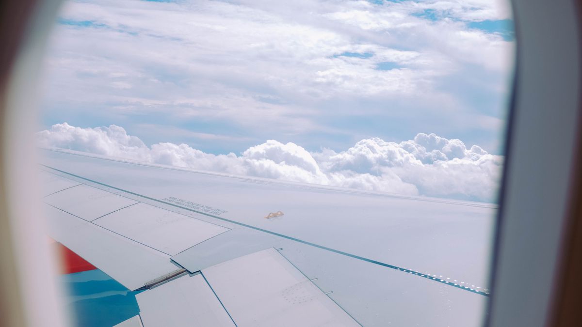 Serene view of fluffy clouds through an airplane window, capturing the essence of travel.