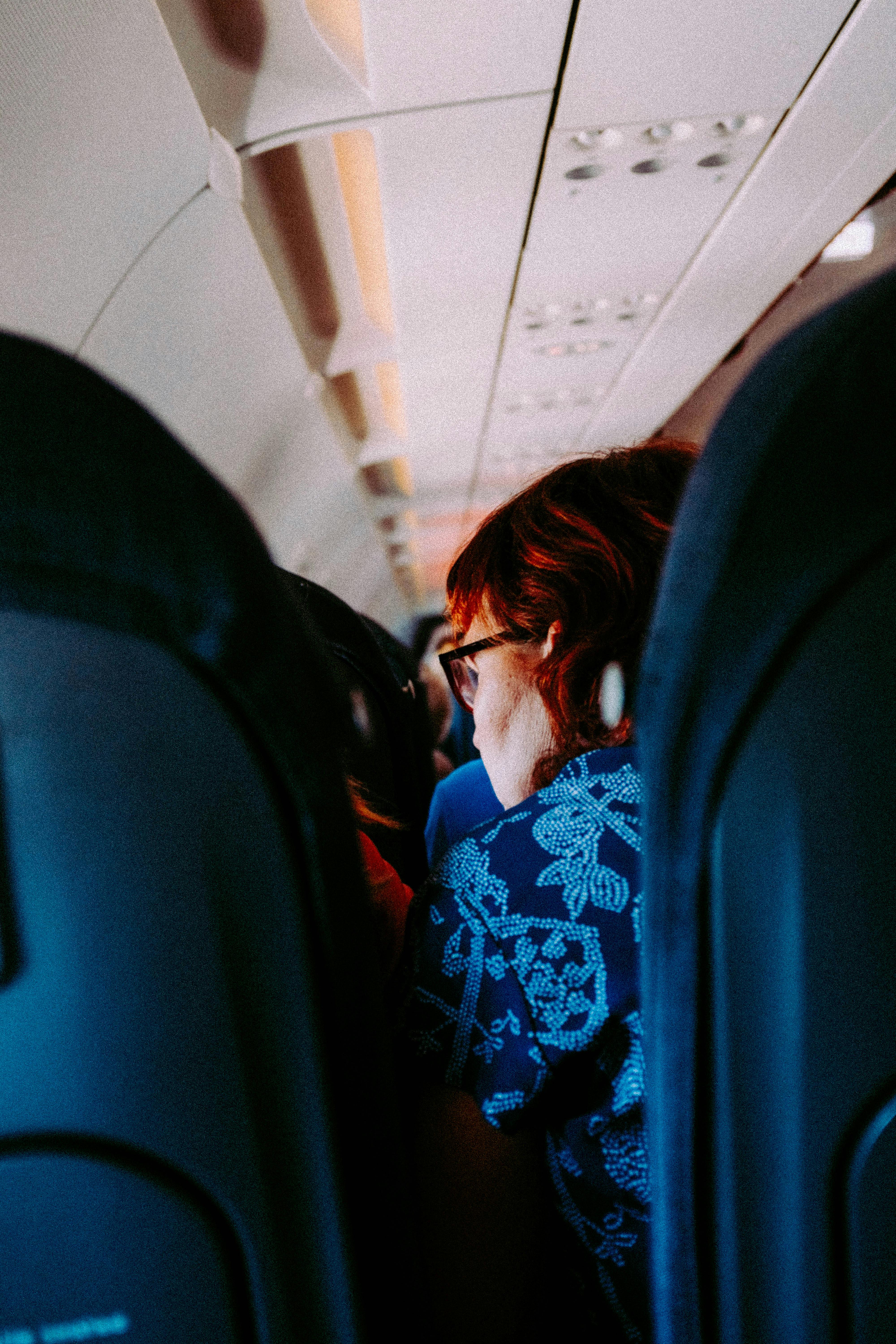 Woman sitting in an airplane cabin interior during daytime travel.
