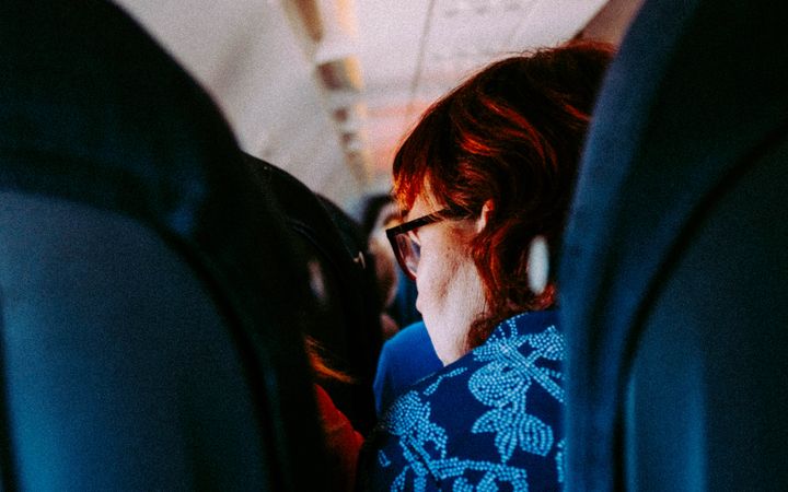 Woman sitting in an airplane cabin interior during daytime travel.