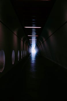 黑暗、未来主义的隧道尽头，光芒汇聚，明亮而神秘，暗示着希望