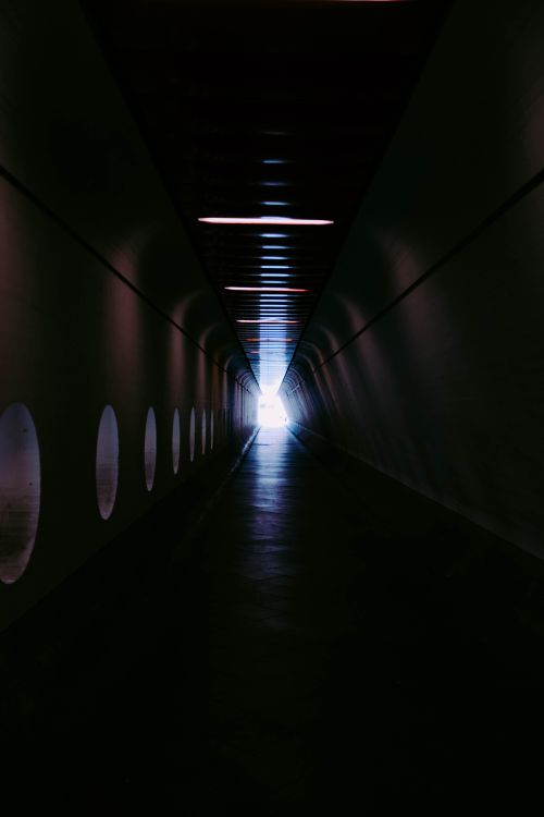 Free Dark, futuristic tunnel converging towards a bright light at the end, suggesting hope and mystery. Stock Photo