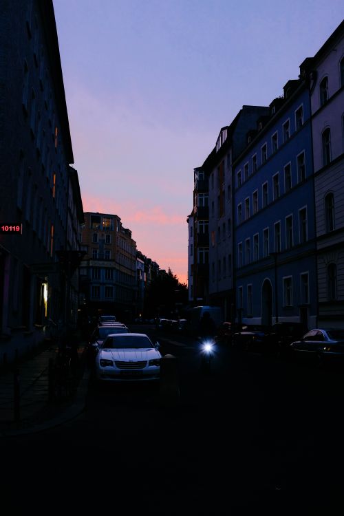 Free Urban street scene at twilight with buildings and parked cars, capturing a tranquil city mood. Stock Photo