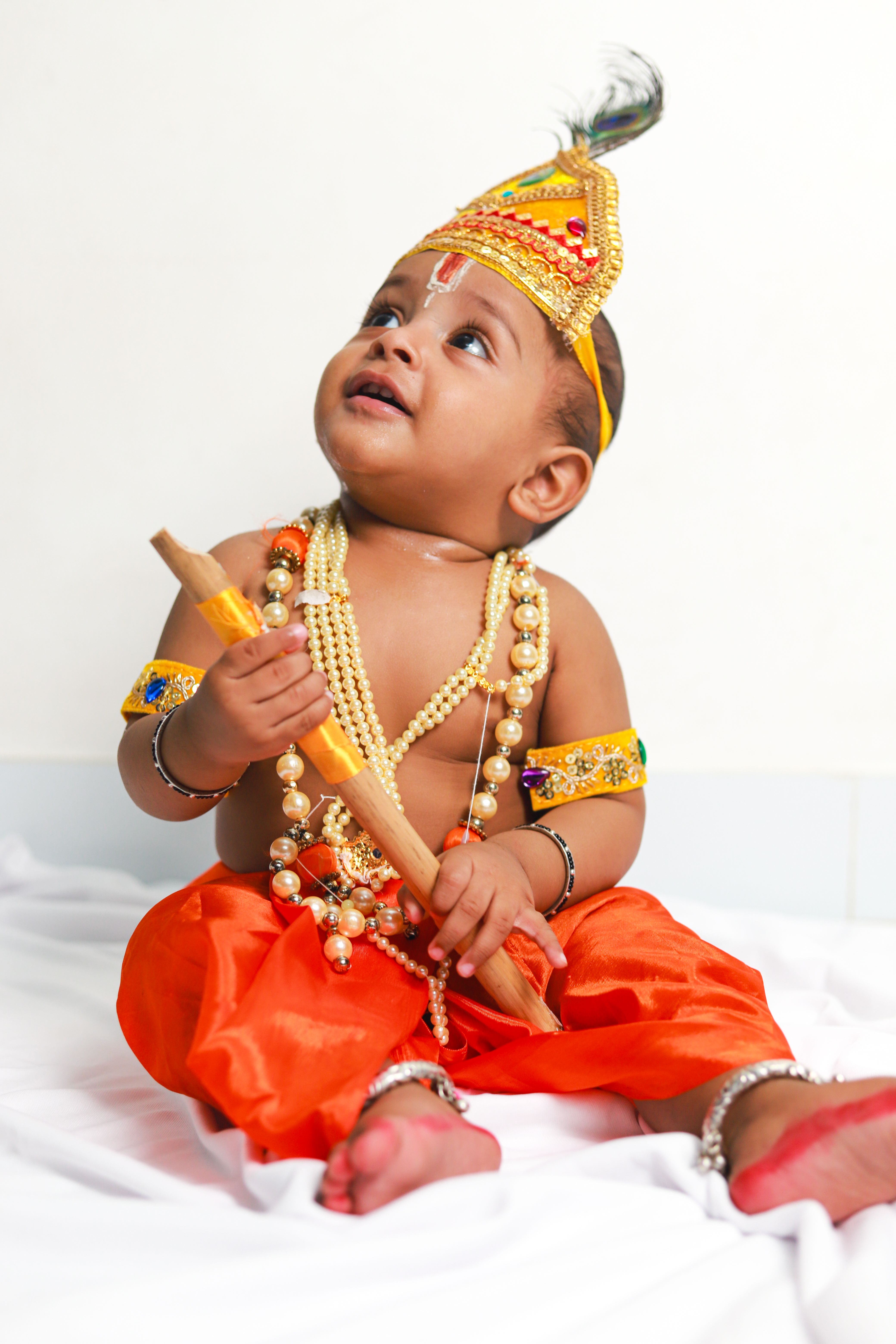 Cute baby dressed as Lord Krishna with beads and traditional attire, showcasing cultural and festive vibes.