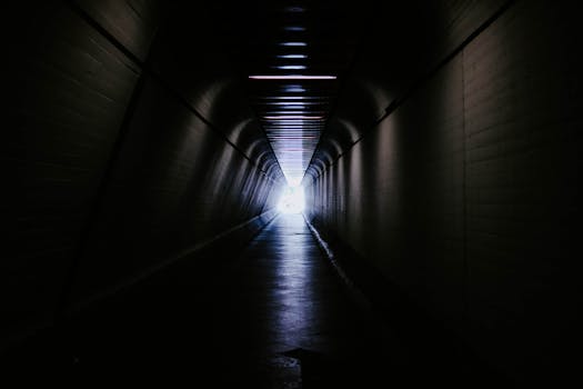 A dimly lit tunnel with a bright light at the end, creating a mysterious atmosphere.